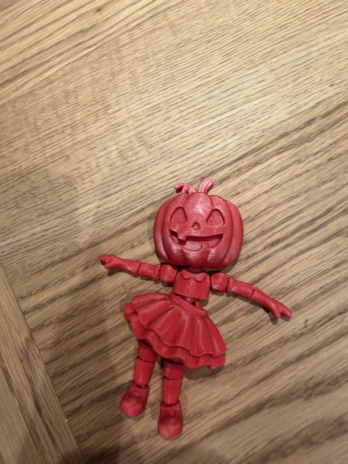 Red 3D printed pumpkin-headed figure with a skirt and jointed arms and legs